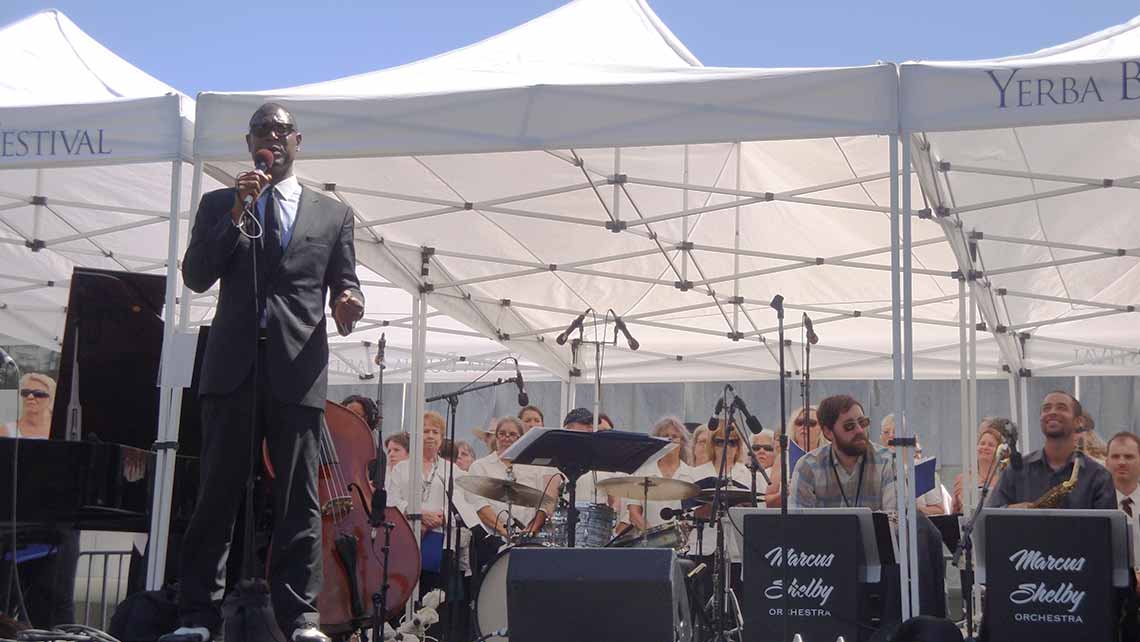Photo of Marcus Shelby speaking in front of his orchestra