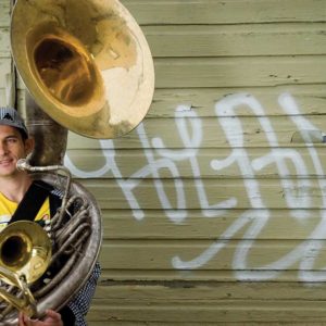 Photo of Adam Theis holding a tuba and trombones