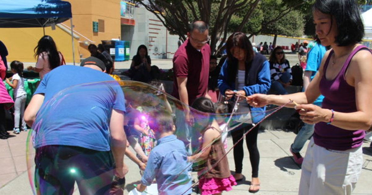 Photo of families making giant bubbles outdoors.