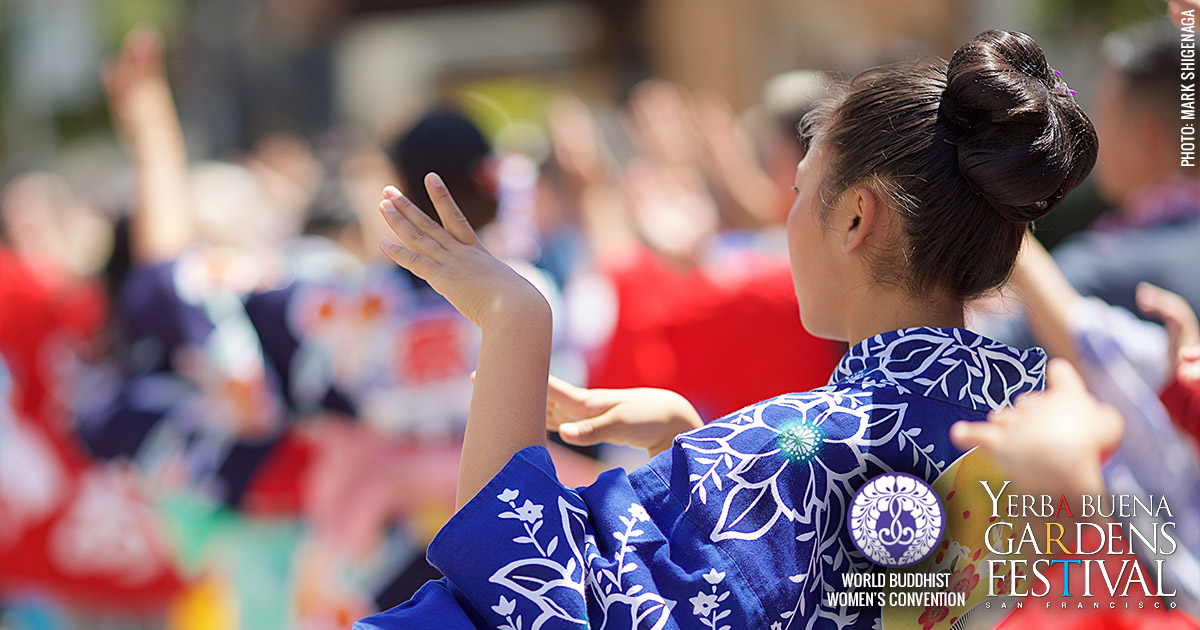Close-up photo of a young woman wearing a blue kimono standing with hands in a dance pose. Photo by Mark Shigenaga.