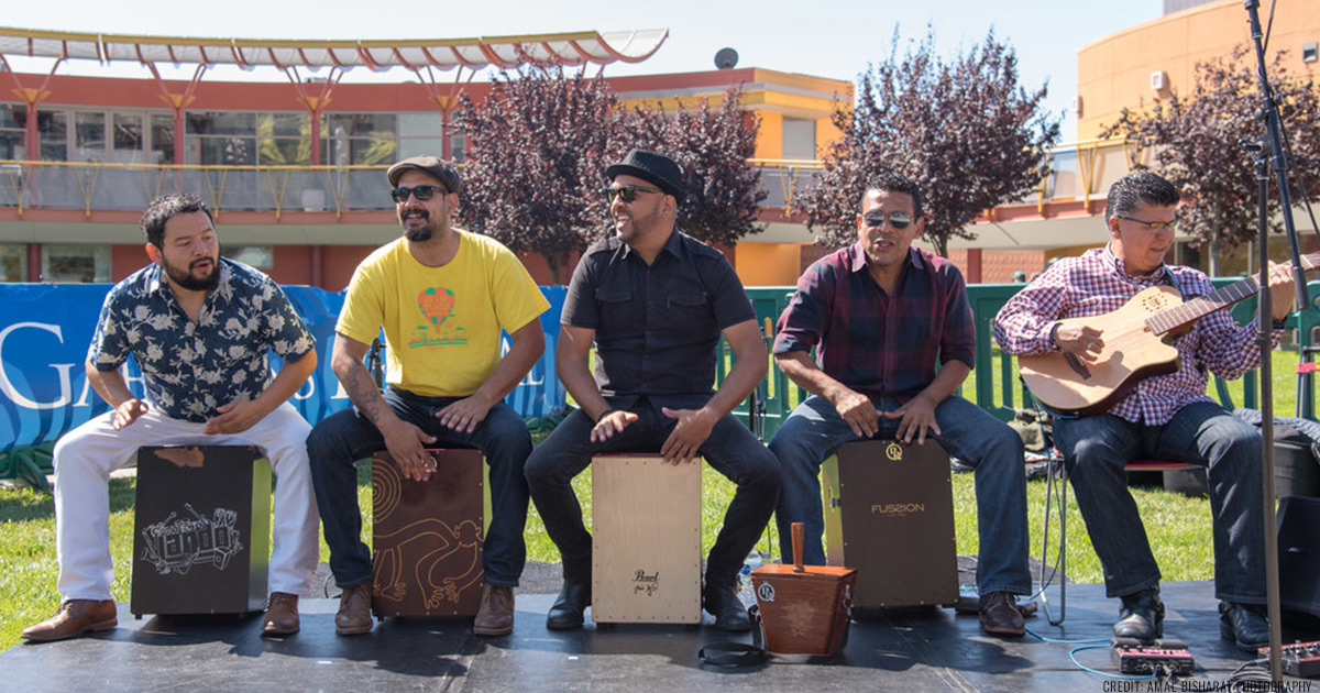 Ka-Hon band members each playing on their own cajon, performing outdoors in the Children's Garden