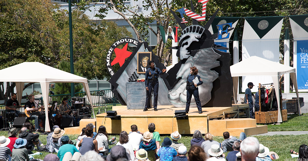 SF Mime Troupe performing on the YBG Festival Esplanade lawn in front of a large audience