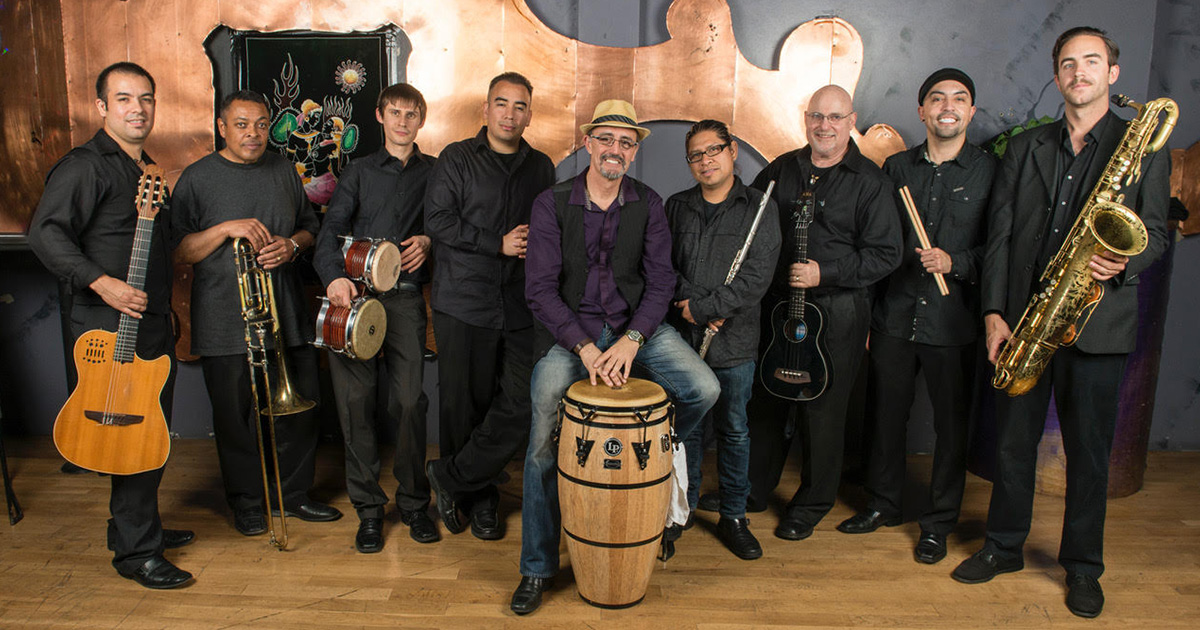 Edgardo Cambon and his band, standing and smiling holding their instruments