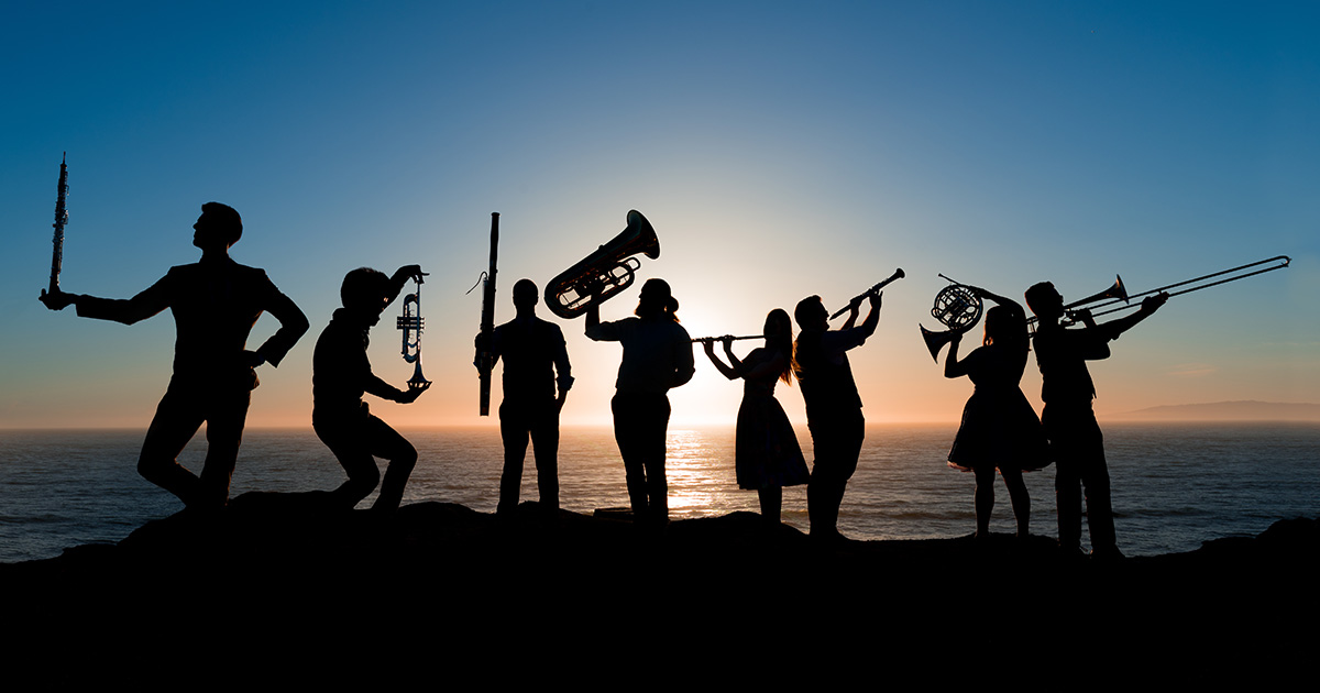 Silhouettes of the members of Nomad Session, the sun setting over the water