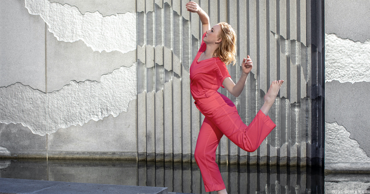 Dancer wearing a pink wardrobe in a dance pose in front of a concrete wall in Yerba Buena Gardens
