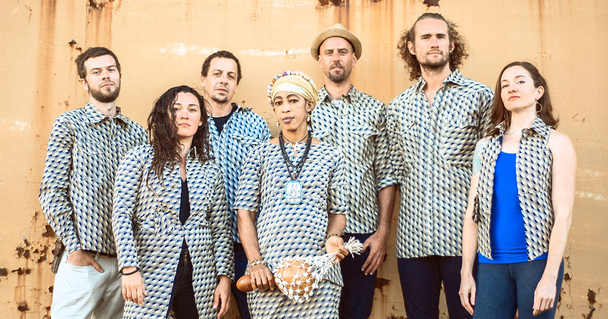 Members of Orchestra Gold, each wearing a clothing using the same geometric pattern, standing in front of a weathered beige wall.