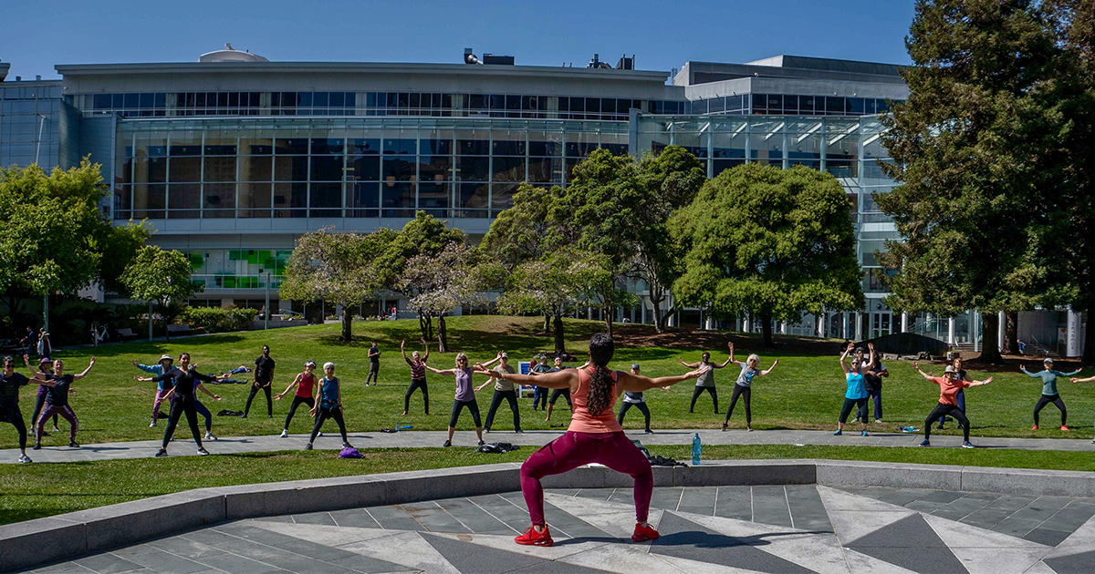 Dance instructor leading an outdoor dance class on the Yerba Buena Gardens lawn,
