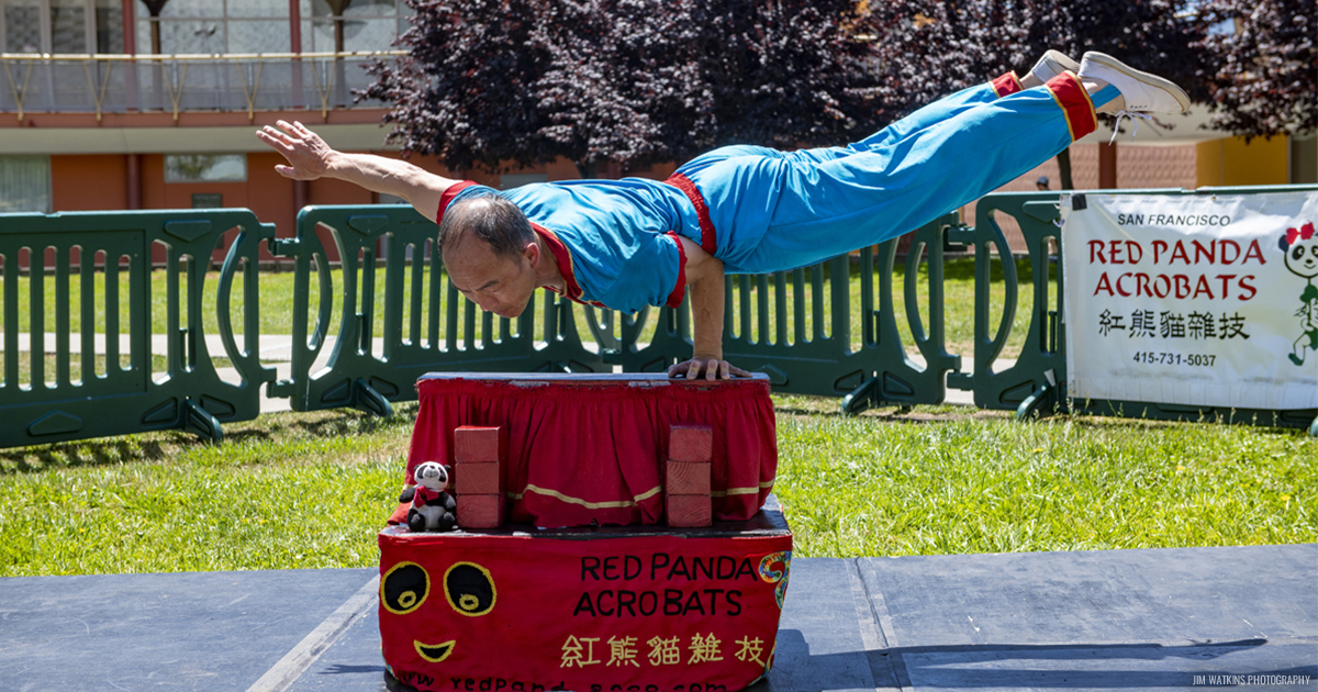 Wayne of Red Panda Acrobats balancing his body on one arm on top of two boxes