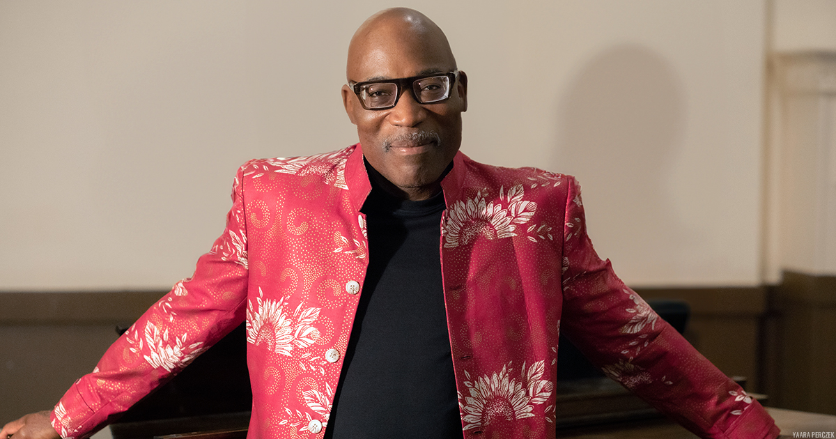 Darrell Grant smiling, front-facing, wearing a floral patterned red jacket