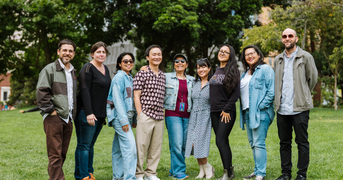 091825_Group Photos_Credit-Nix Guirre_DSC04324 copy YBG Festival staff smiling and standing outdoors on a green lawn, lush green trees behind them.