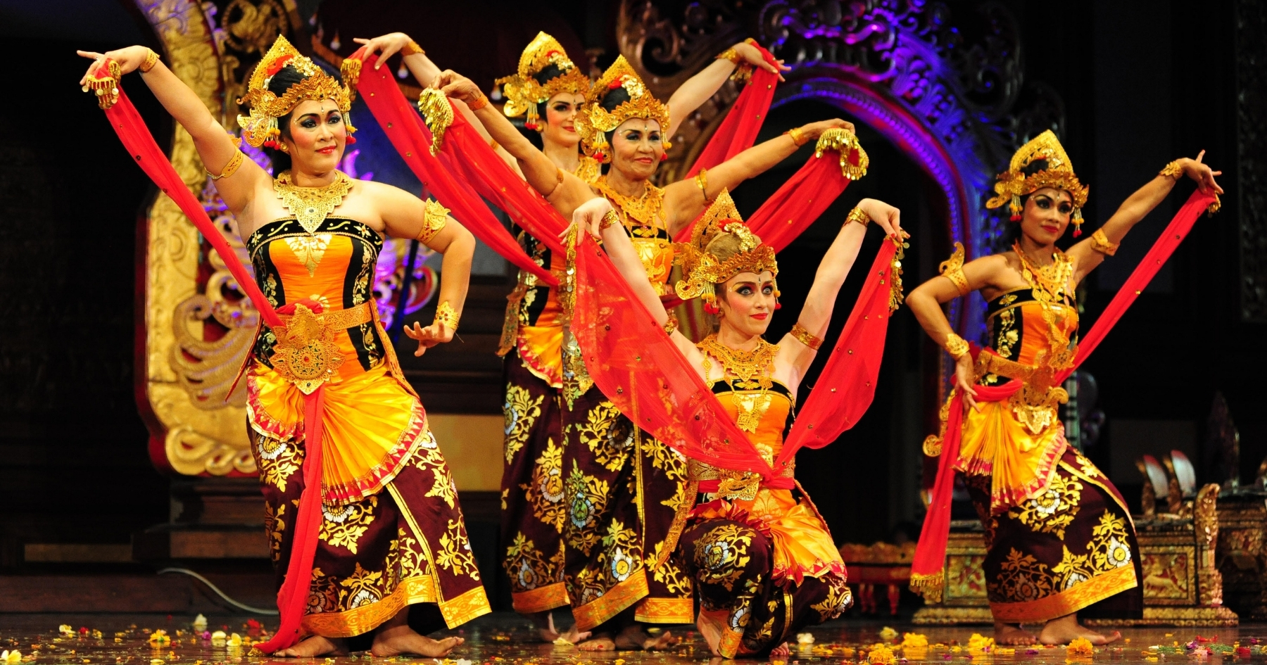 A group of 5 women dancers dressed in Balinese dance clothing, performing on stage
