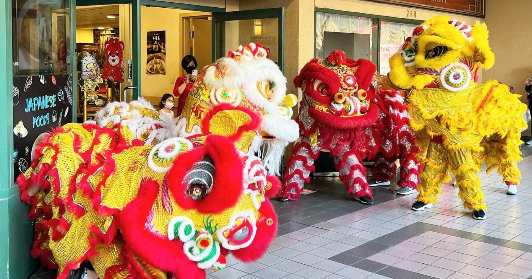 Four Chinese lion mascots dancing in a semi-circle