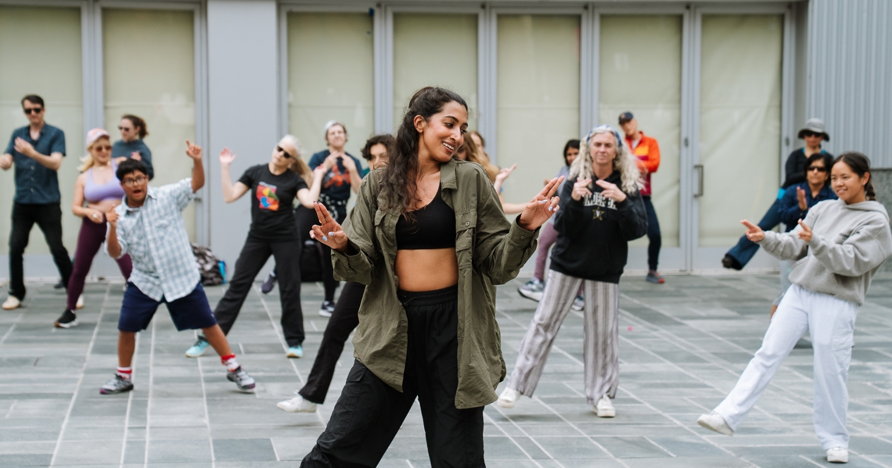 An instructor leading a dance class behind them in an outdoor court